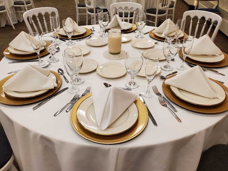 Dining room table set for 8 guest with cream and beige dishes and candle center piece