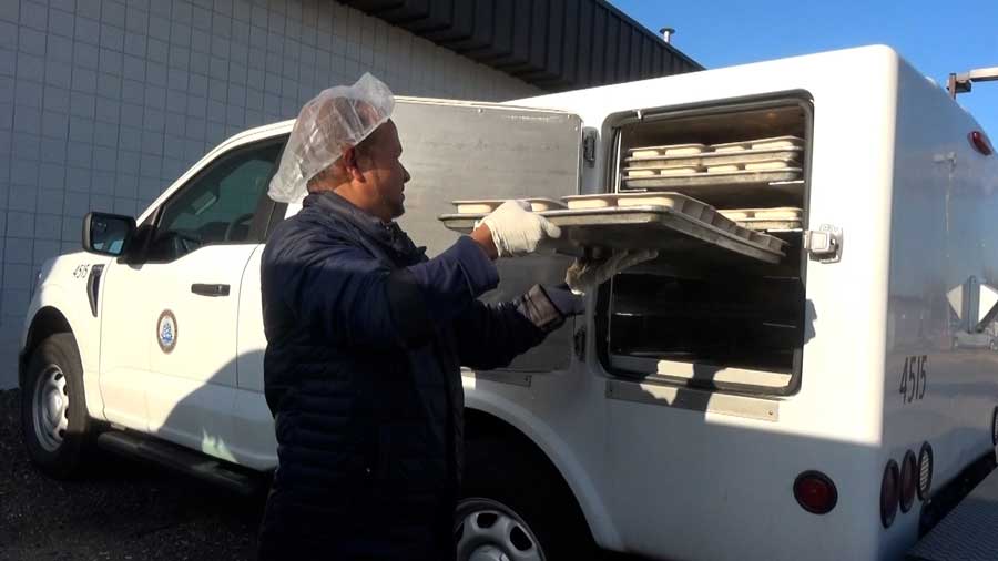 Meal delivery staff removing meals from the truck.