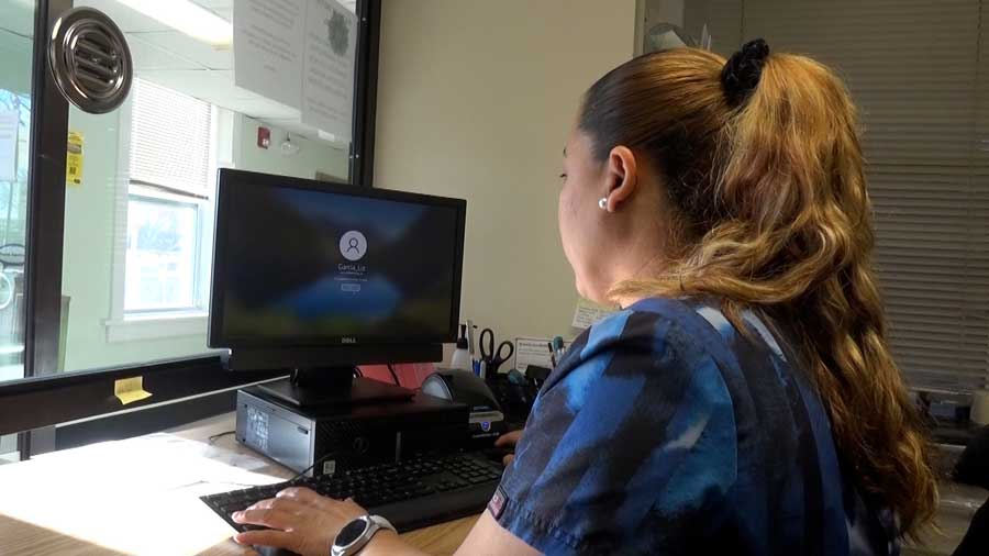 Women working as receptionist behind glass with a computer